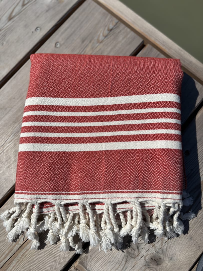Hamamtuch ALMA – Dein vielseitiges Strandtuch für Sommer in Rot zusammengelegt am Strand -DENIO