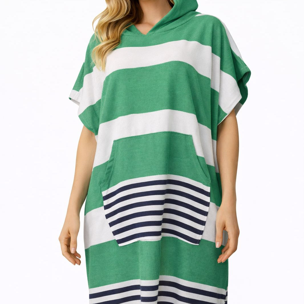 Frau trägt grünen und weiß gestreiften Baumwoll-Poncho mit Kapuze und Fransen vor weißem Hintergrund.
