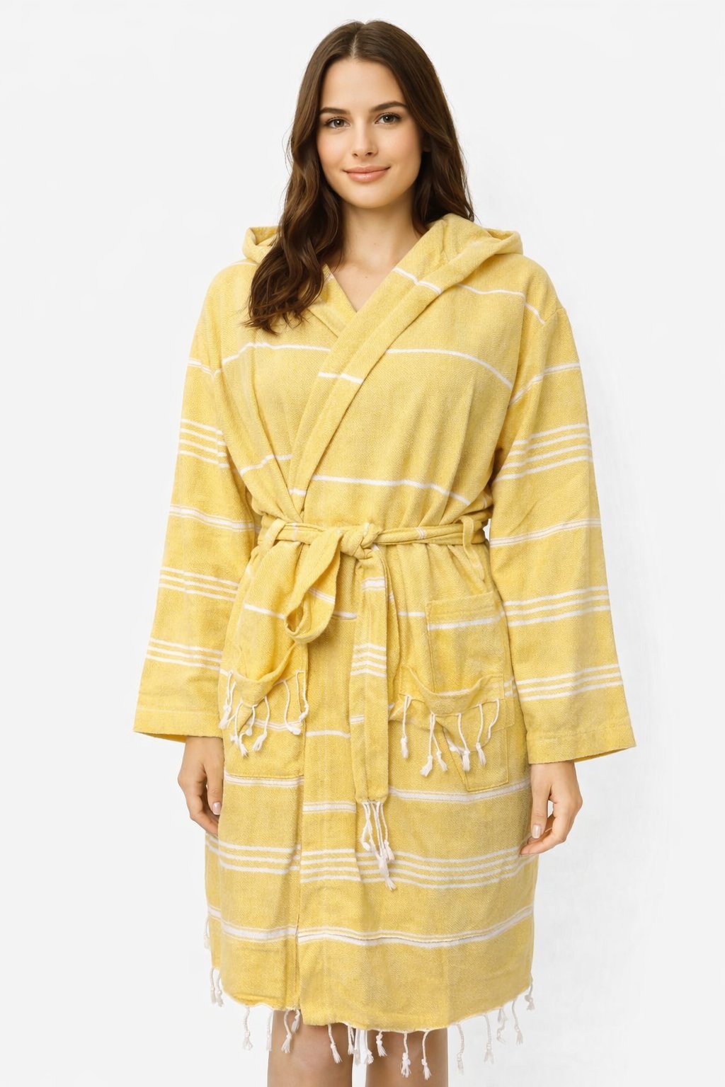 Frau trägt Bademantel in Farbe Gelb aus glatter Baumwolle mit weißen Streifen und Kapuze vor weißem Hintergrund.