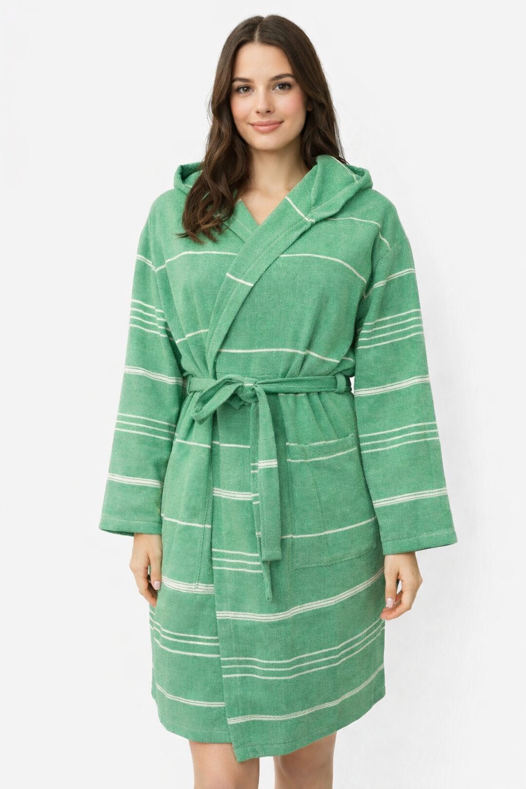 Frau trägt Bademantel in Farbe grün aus glatter Baumwolle mit weißen Streifen und Kapuze vor weißem Hintergrund.