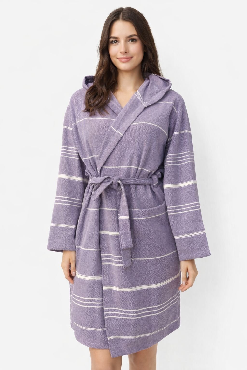 Frau trägt lila Bademantel aus glatter Baumwolle mit weißen Streifen und Kapuze vor weißem Hintergrund.